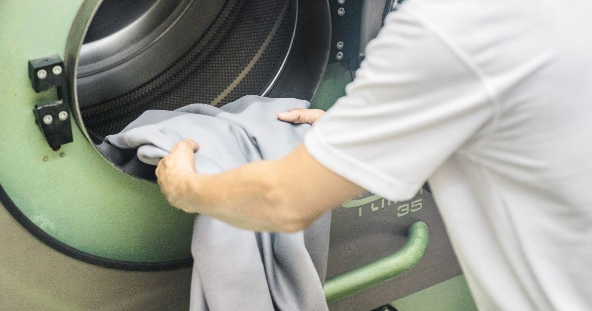 staff putting curtain into washing machine
