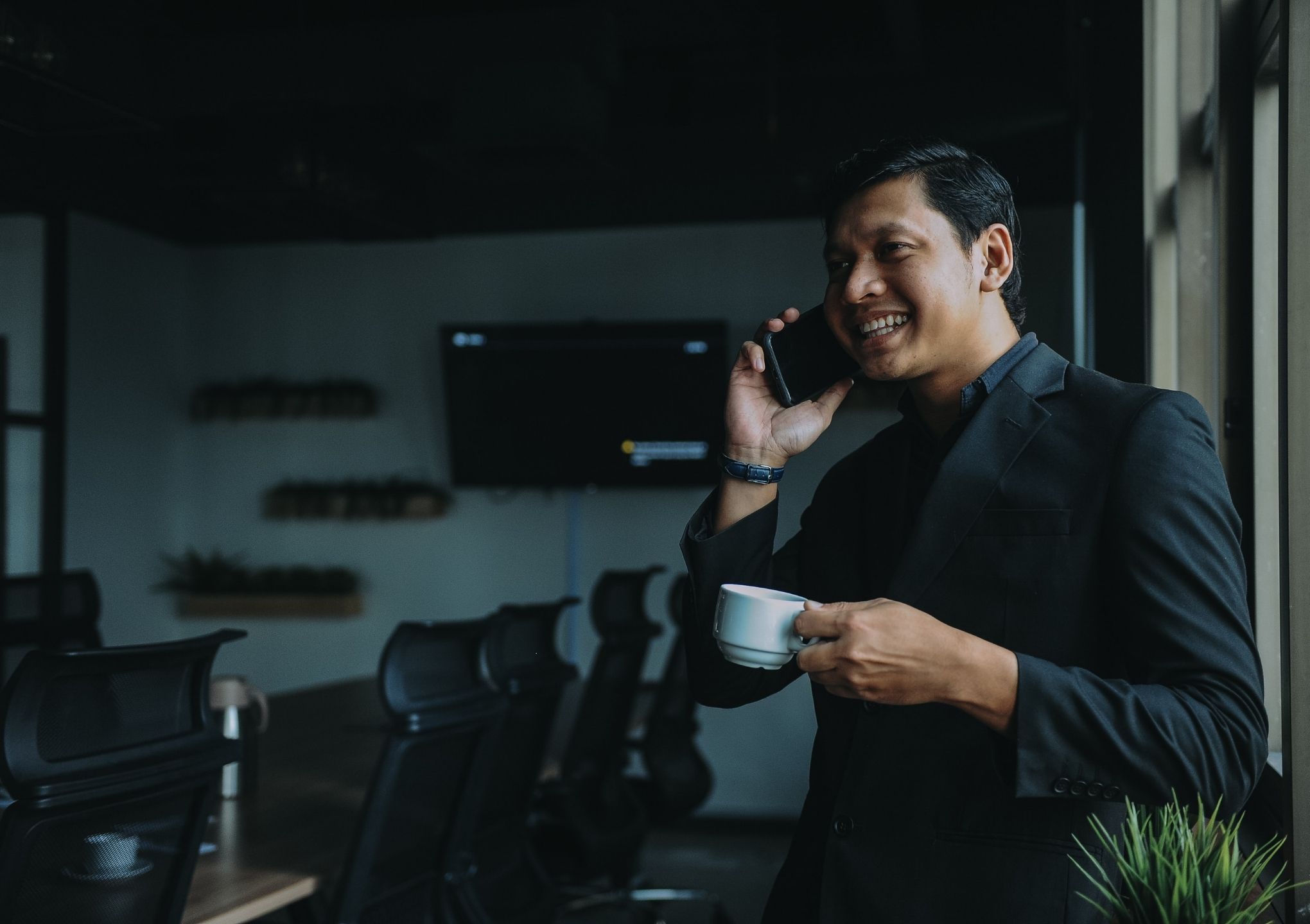 seorang lelaki sedang bercakap di telefon dengan kopi di tangannya
