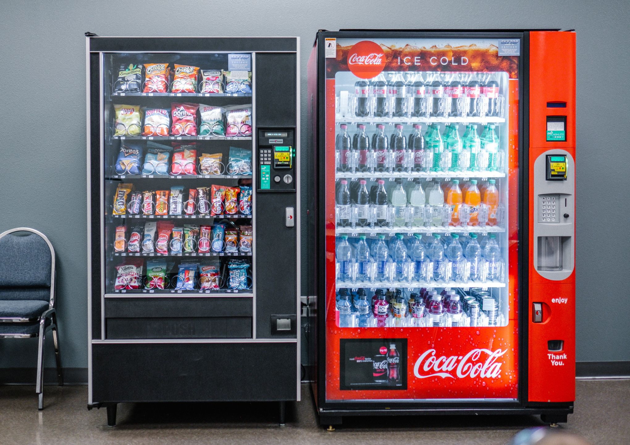 two vending machines next to two chairs - Post Featured Image
