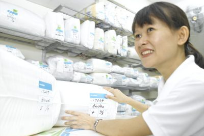 Mrs.Pamela is smiling while holding the folded garments in the plastic bag.