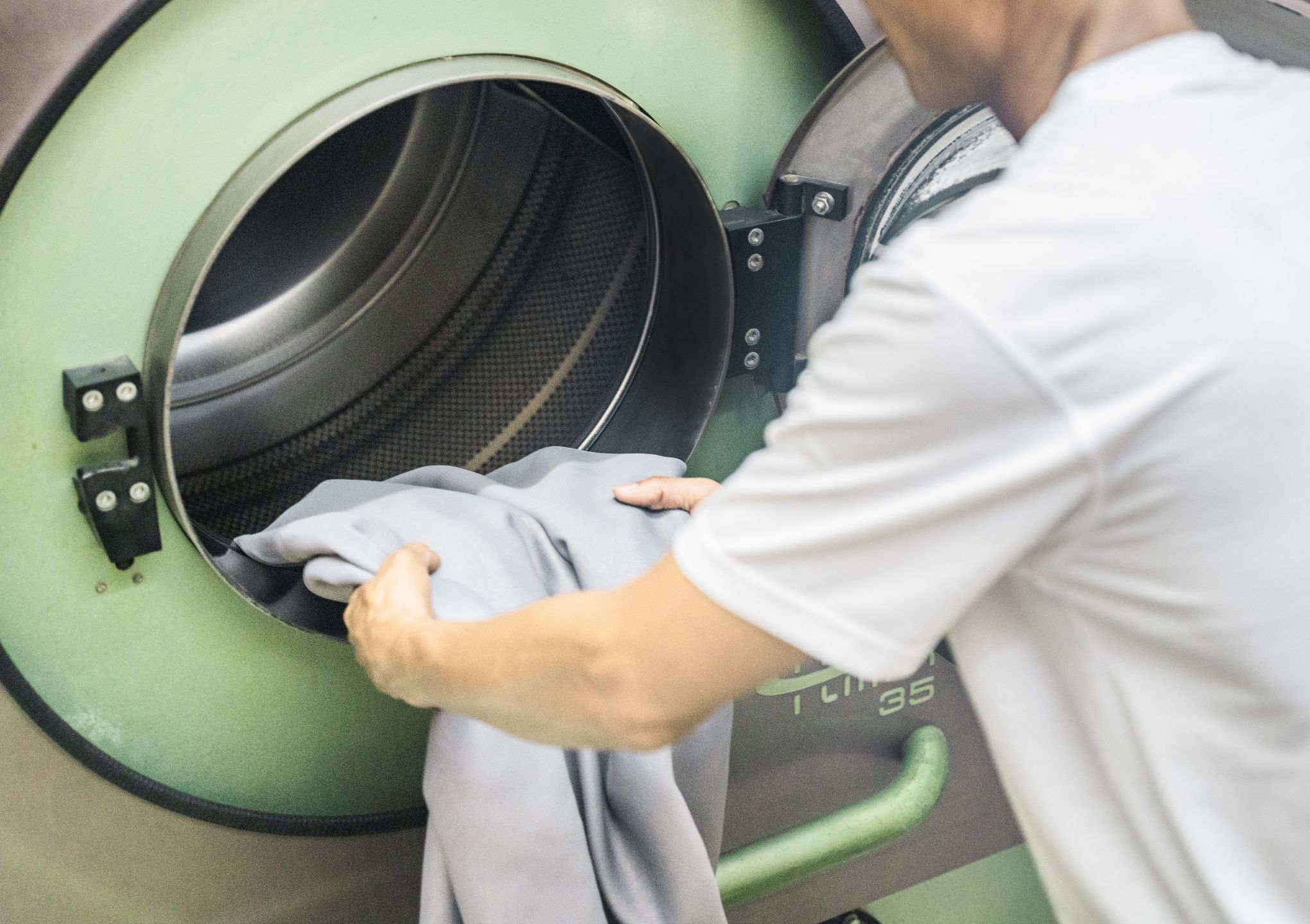 staff putting the curtain into the dry cleaning machine - Post Featured Image